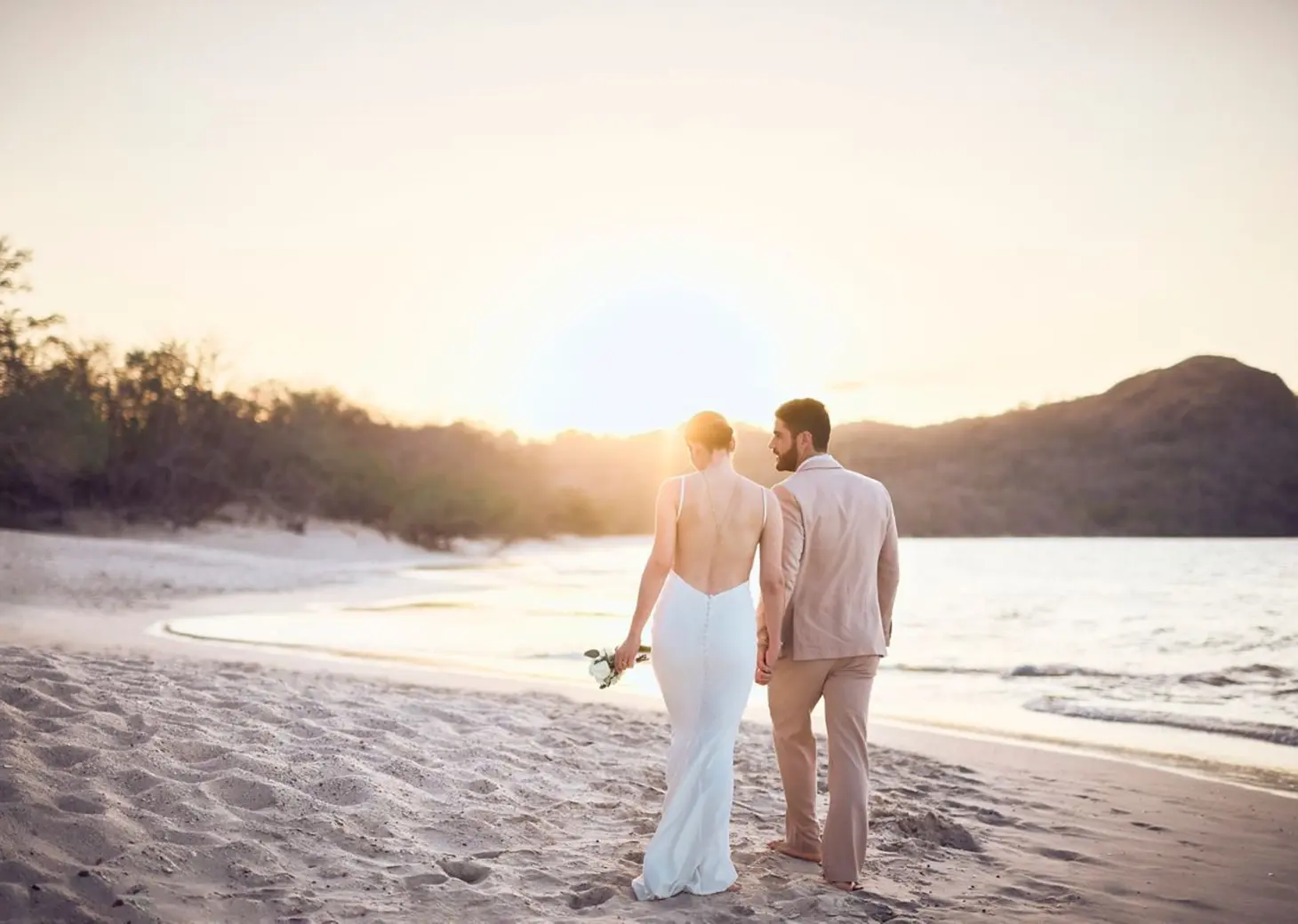 Bride and groom walking at sunset on the beach at The Westin Reserva Conchal, Liberia
