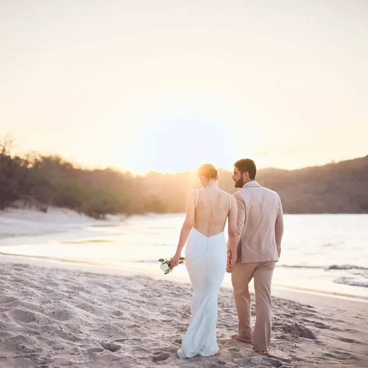 Bride and groom walking at sunset on the beach at The Westin Reserva Conchal, Liberia