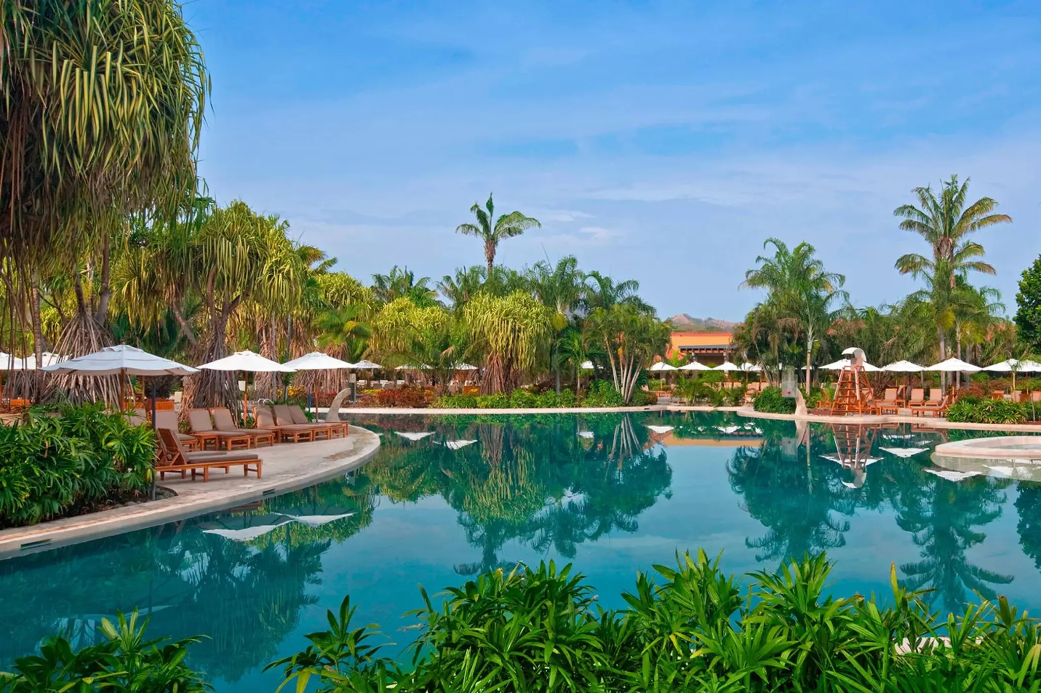 Lagoon-style pool surrounded by palm trees and white umbrellas at Westin Reserva Conchal, Liberia