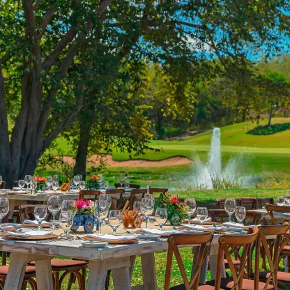 Outdoor wedding reception setup with wooden tables by a fountain and golf course at Westin Reserva Conchal, Liberia