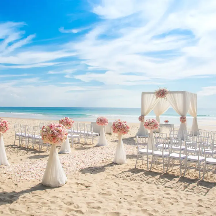 Beachfront wedding ceremony setup at Wyndham Alltra Cancun with pink floral arrangements and white huppah