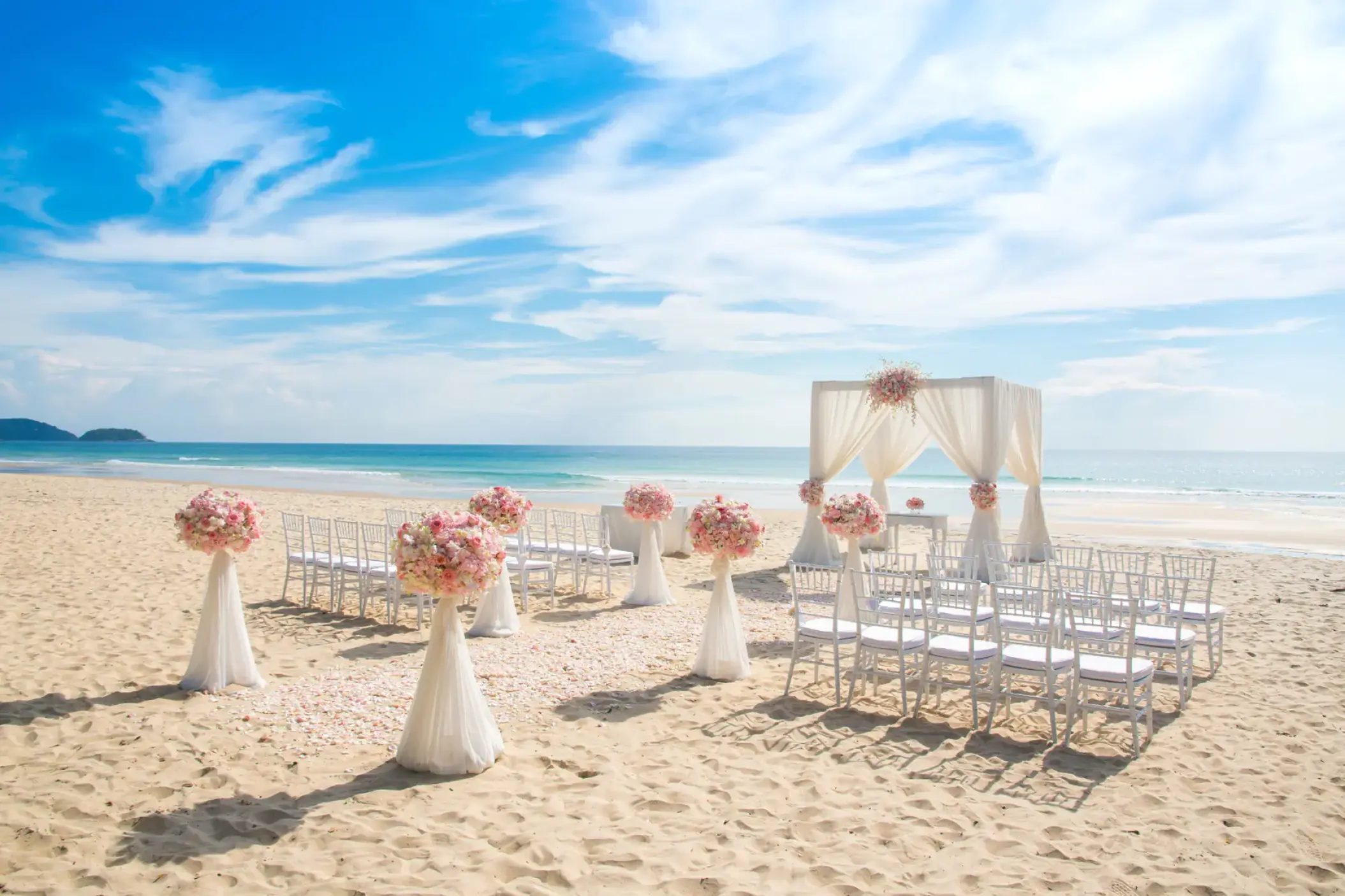 Beachfront wedding ceremony setup at Wyndham Alltra Cancun with pink floral arrangements and white huppah