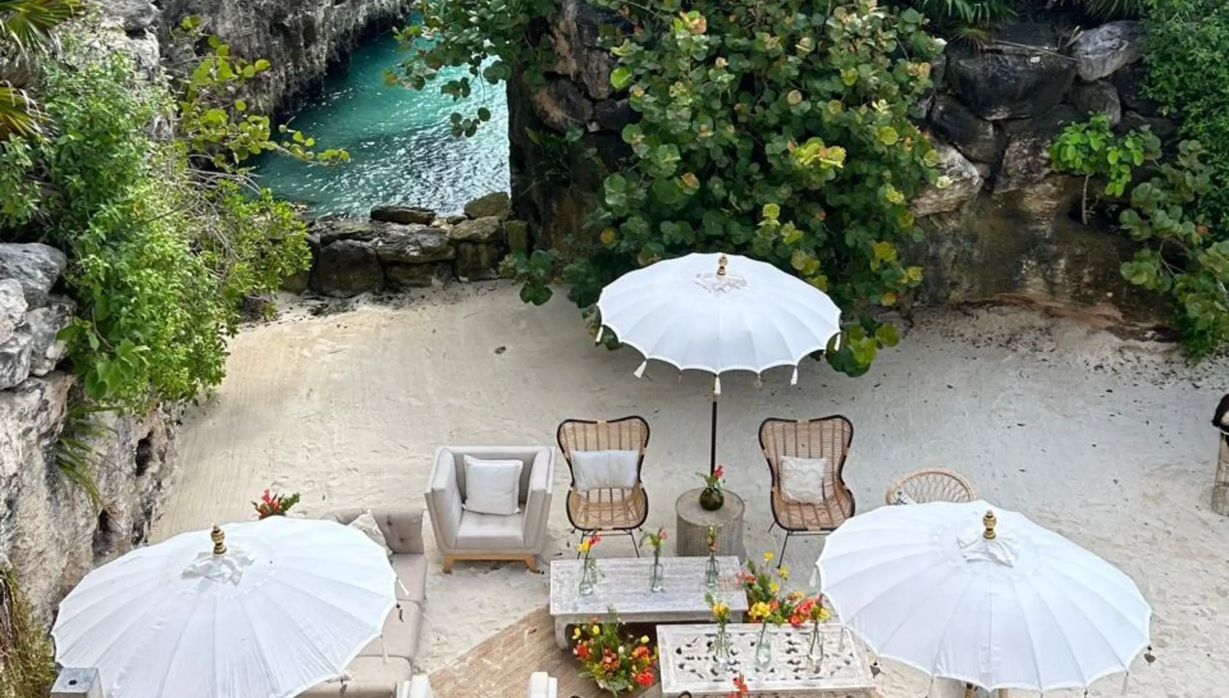Sandy cove lounge reception with white umbrellas and wicker chairs at Hotel Xcaret Arte, Riviera Maya
