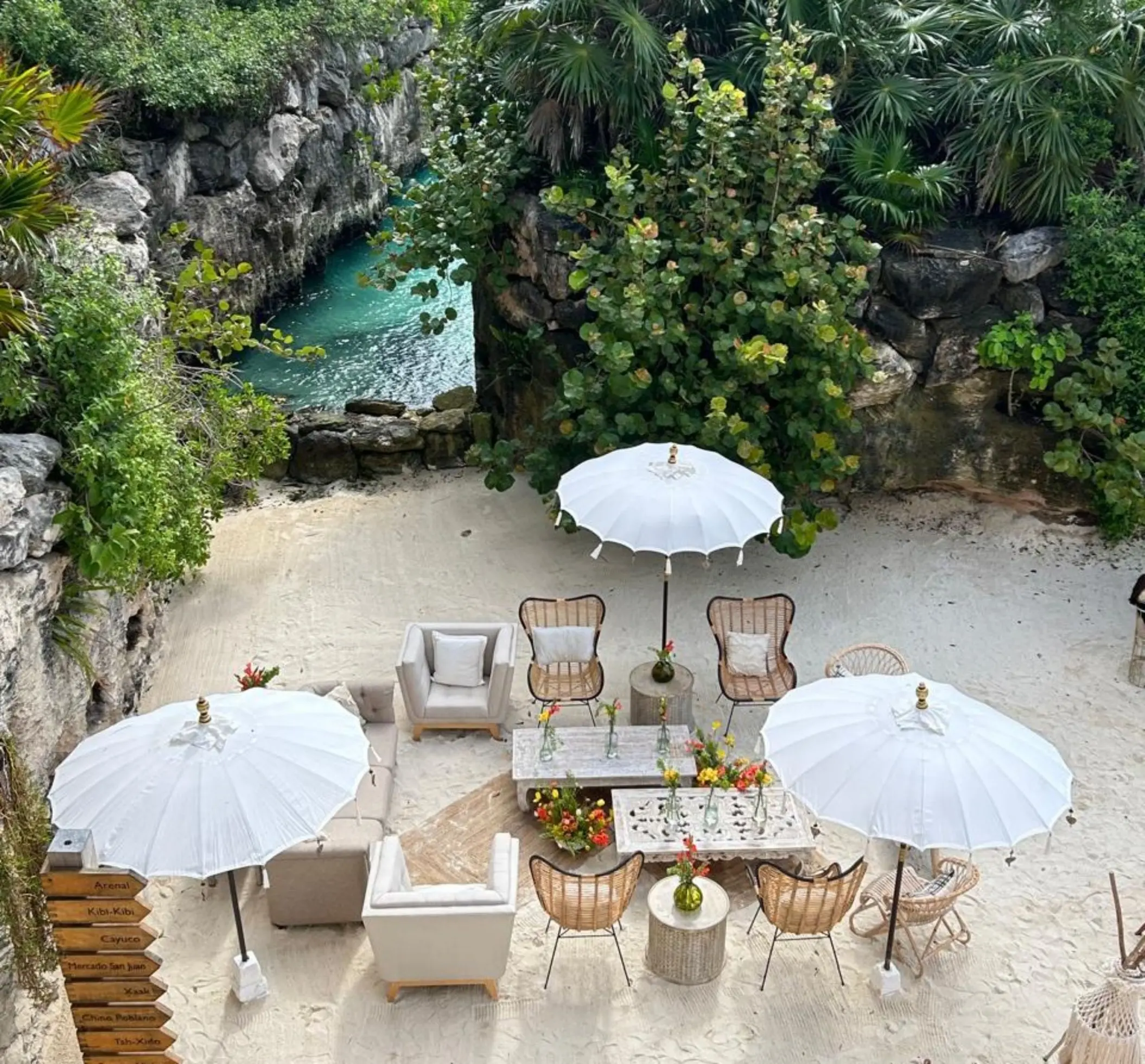 Sandy cove lounge reception with white umbrellas and wicker chairs at Hotel Xcaret Arte, Riviera Maya