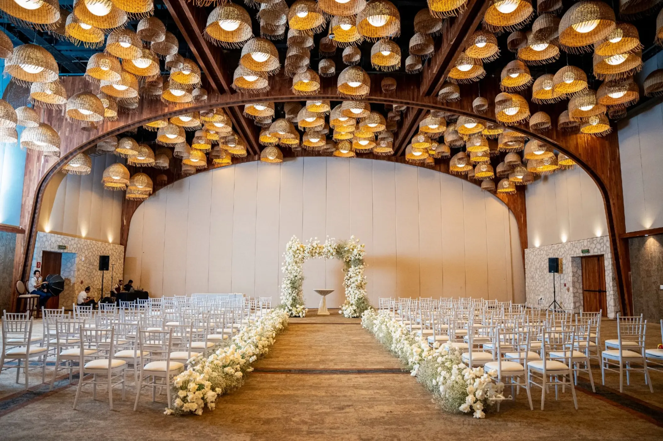 Indoor wedding ceremony in the Diego ballroom with floral arch and hanging lamps at Hotel Xcaret Arte, Riviera Maya