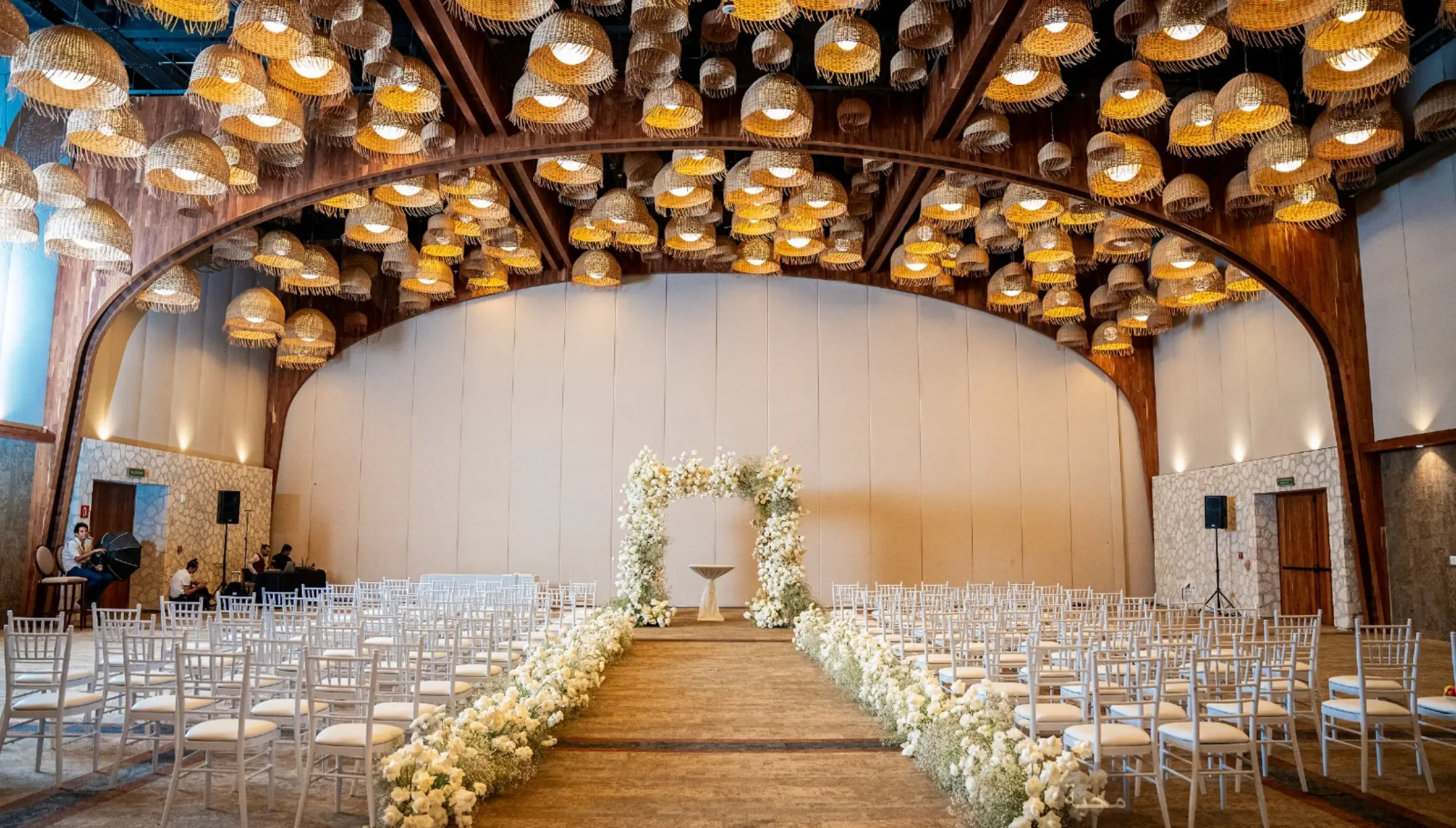Indoor wedding ceremony in the Diego ballroom with floral arch and hanging lamps at Hotel Xcaret Arte, Riviera Maya