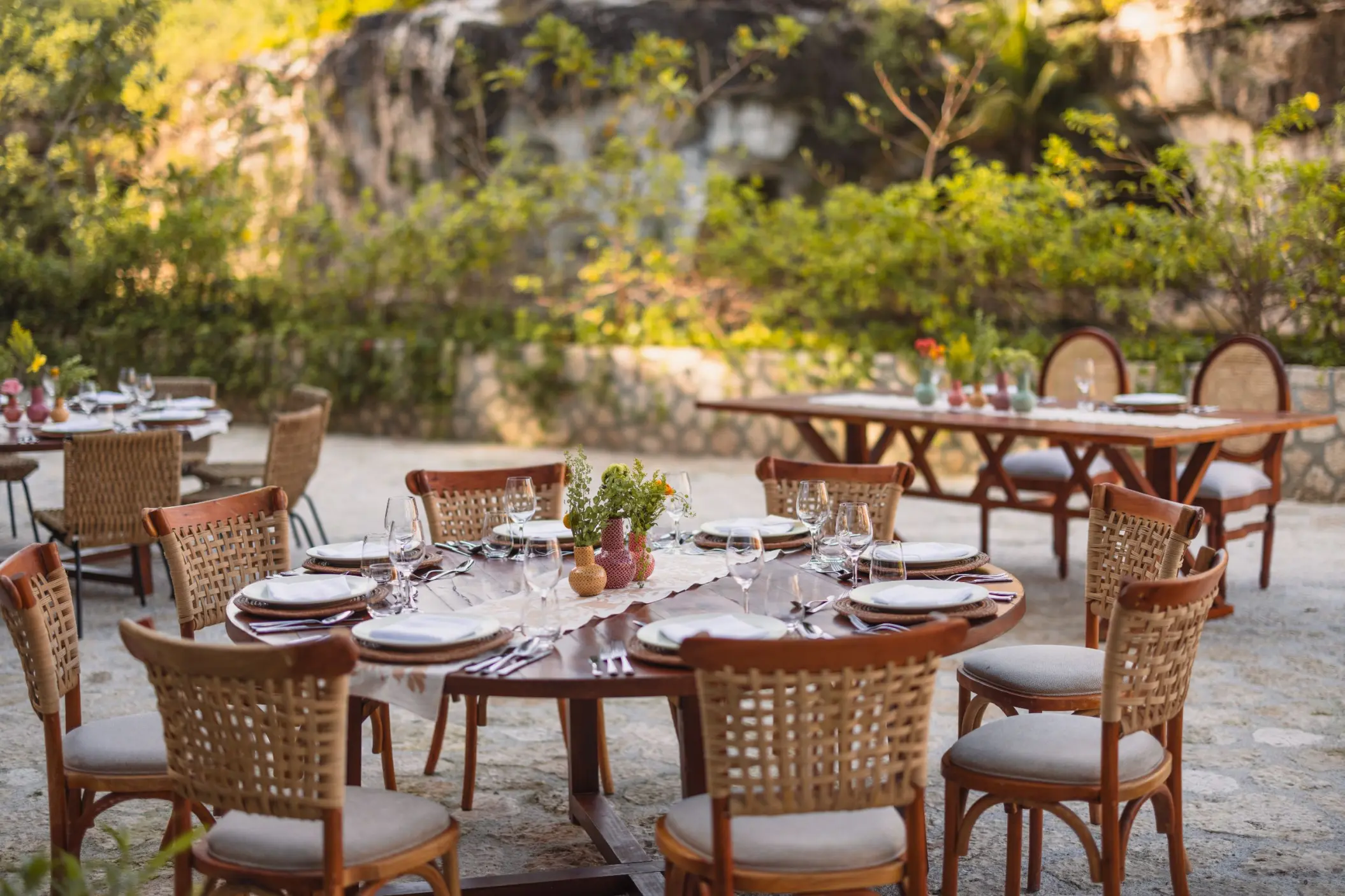 Outdoor wedding reception with woven chairs and wooden tables at Hotel Xcaret Arte, Riviera Maya