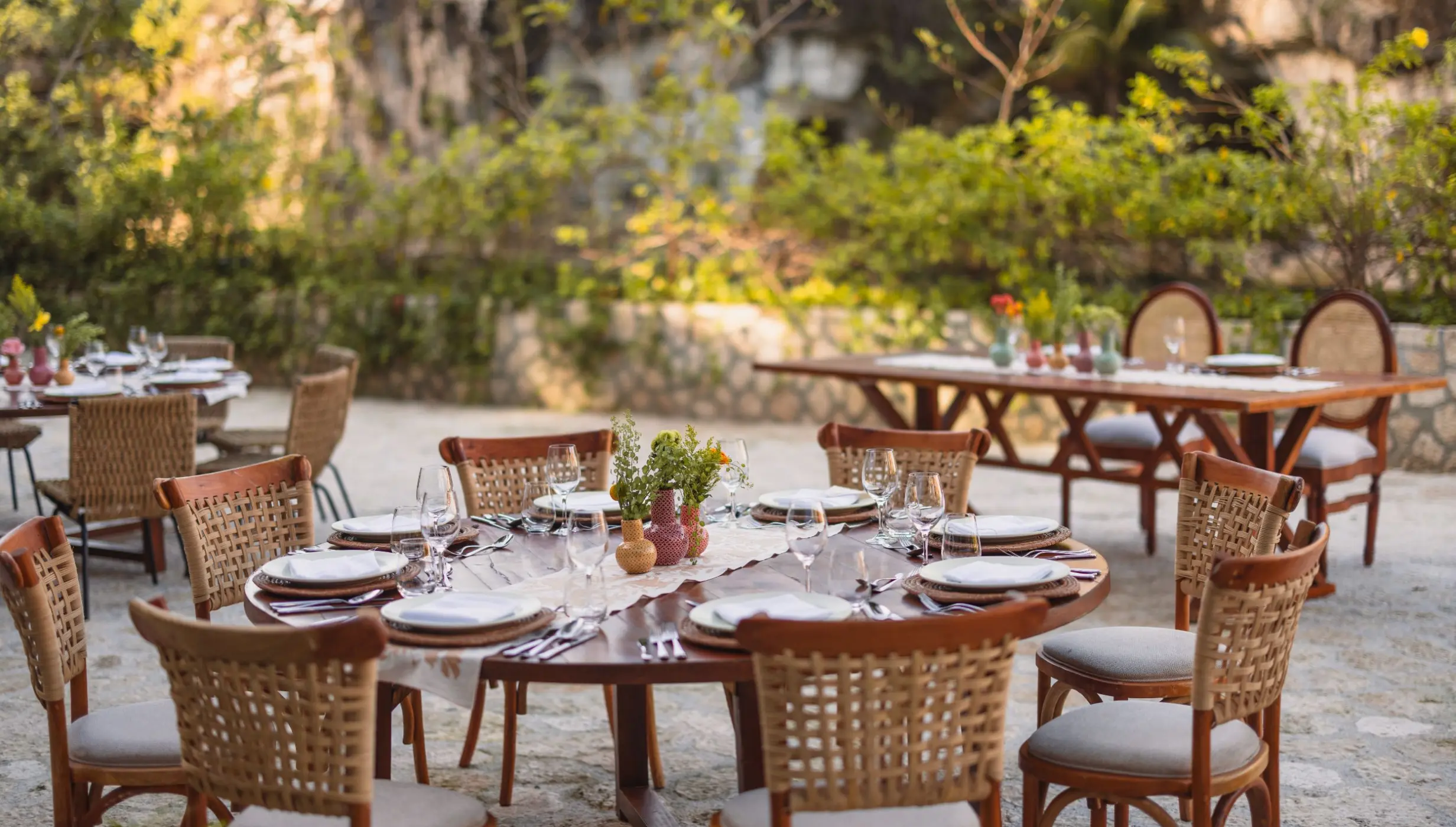 Outdoor wedding reception with woven chairs and wooden tables at Hotel Xcaret Arte, Riviera Maya