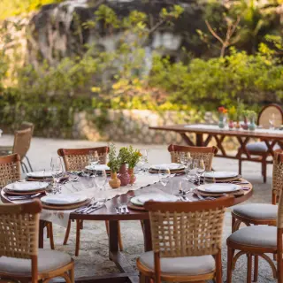 Outdoor wedding reception with woven chairs and wooden tables at Hotel Xcaret Arte, Riviera Maya