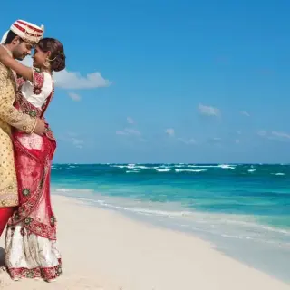 South Asian bride and groom embracing on the beach at Zoetry Agua Punta Cana