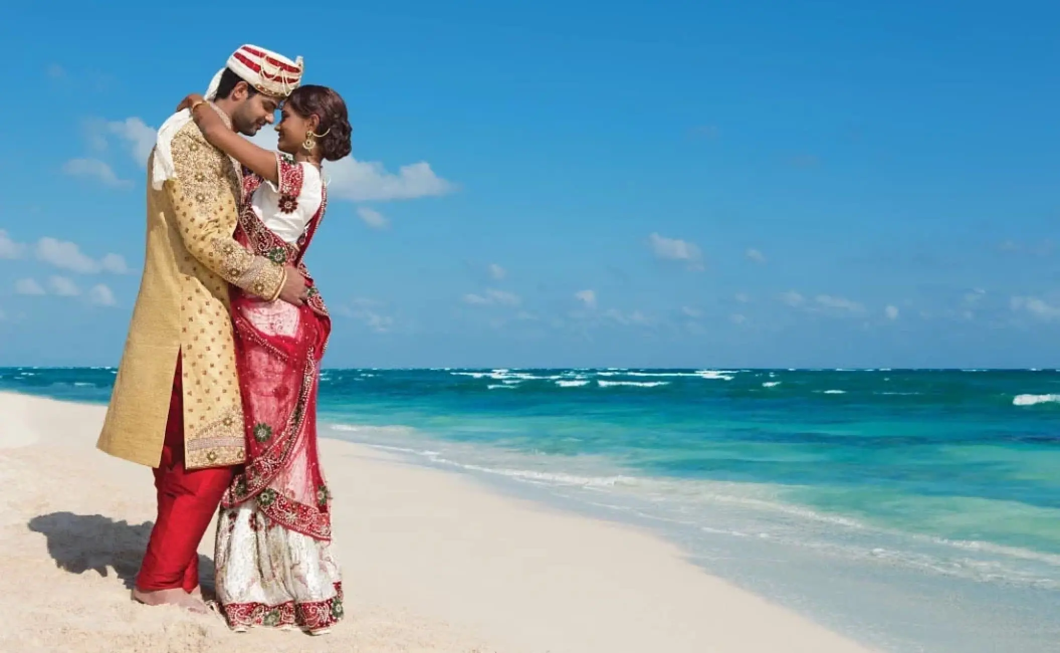South Asian bride and groom embracing on the beach at Zoetry Agua Punta Cana