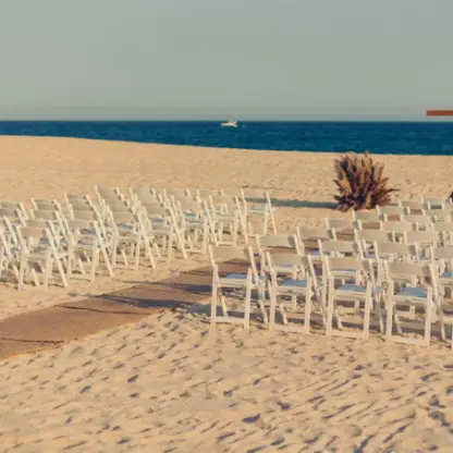Beach wedding ceremony with white chairs and a wooden cross at Zoetry Casa del Mar, Cabo San Lucas
