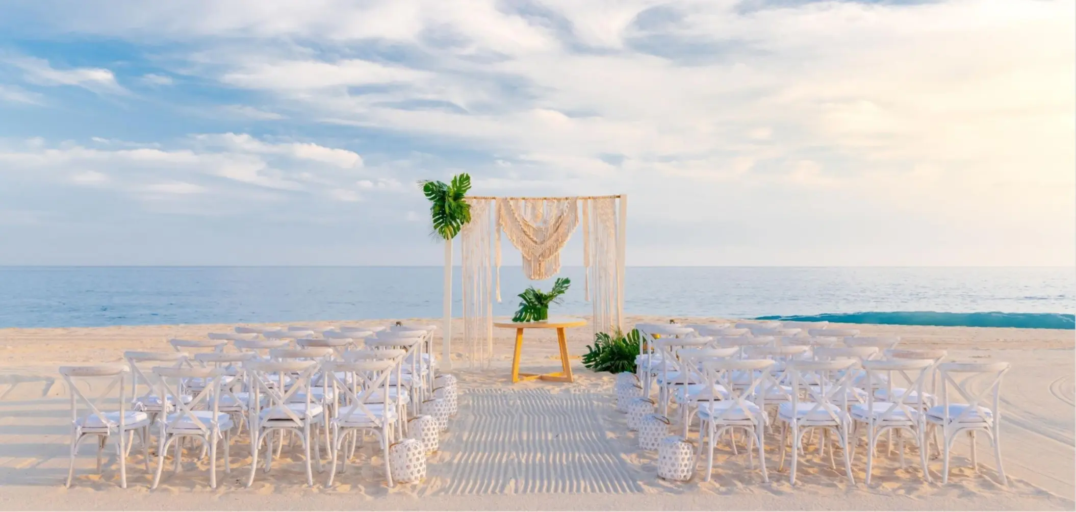 Macramé arch and white chairs for a beach wedding ceremony at Zoetry Casa del Mar, Cabo San Lucas