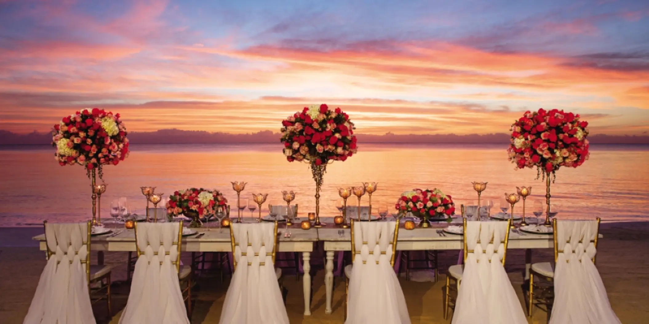 Beachfront wedding reception setup with floral centerpieces at sunset, Zoetry Casa del Mar, Cabo San Lucas