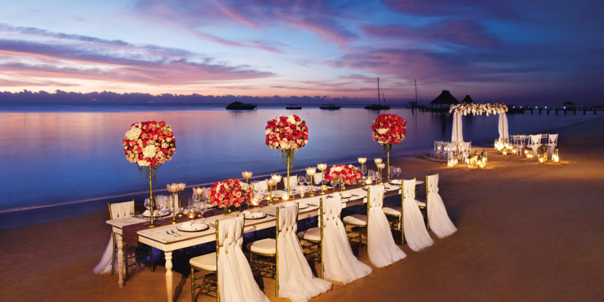 Beachfront wedding reception table with red and white floral centerpieces at Zoetry Casa del Mar, Cabo San Lucas