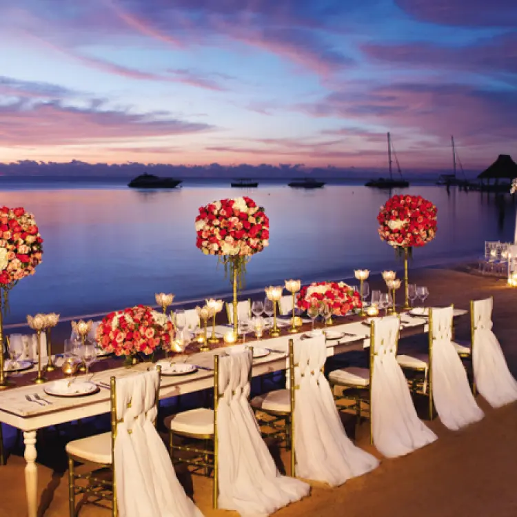 Beachfront wedding reception table with red and white floral centerpieces at Zoetry Casa del Mar, Cabo San Lucas