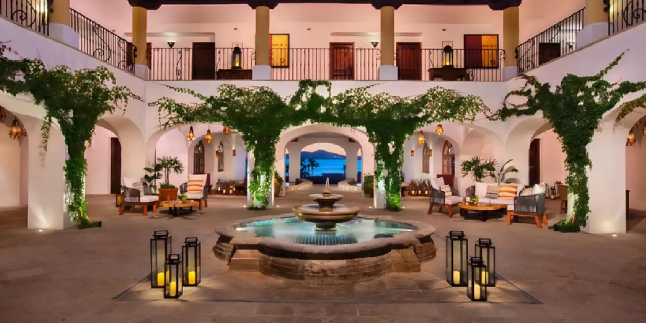 Courtyard with a stone fountain, lanterns, and ivy-covered arches at Zoetry Casa del Mar, Cabo San Lucas