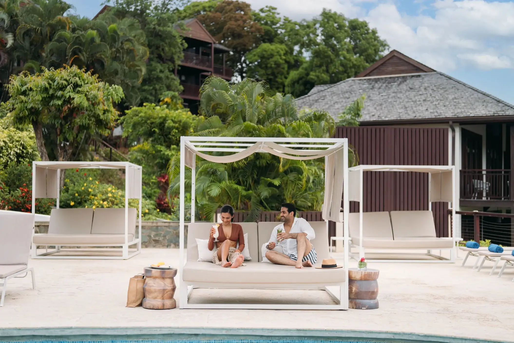 Couple relaxing on a white Bali bed poolside at Zoetry Marigot Bay, Castries