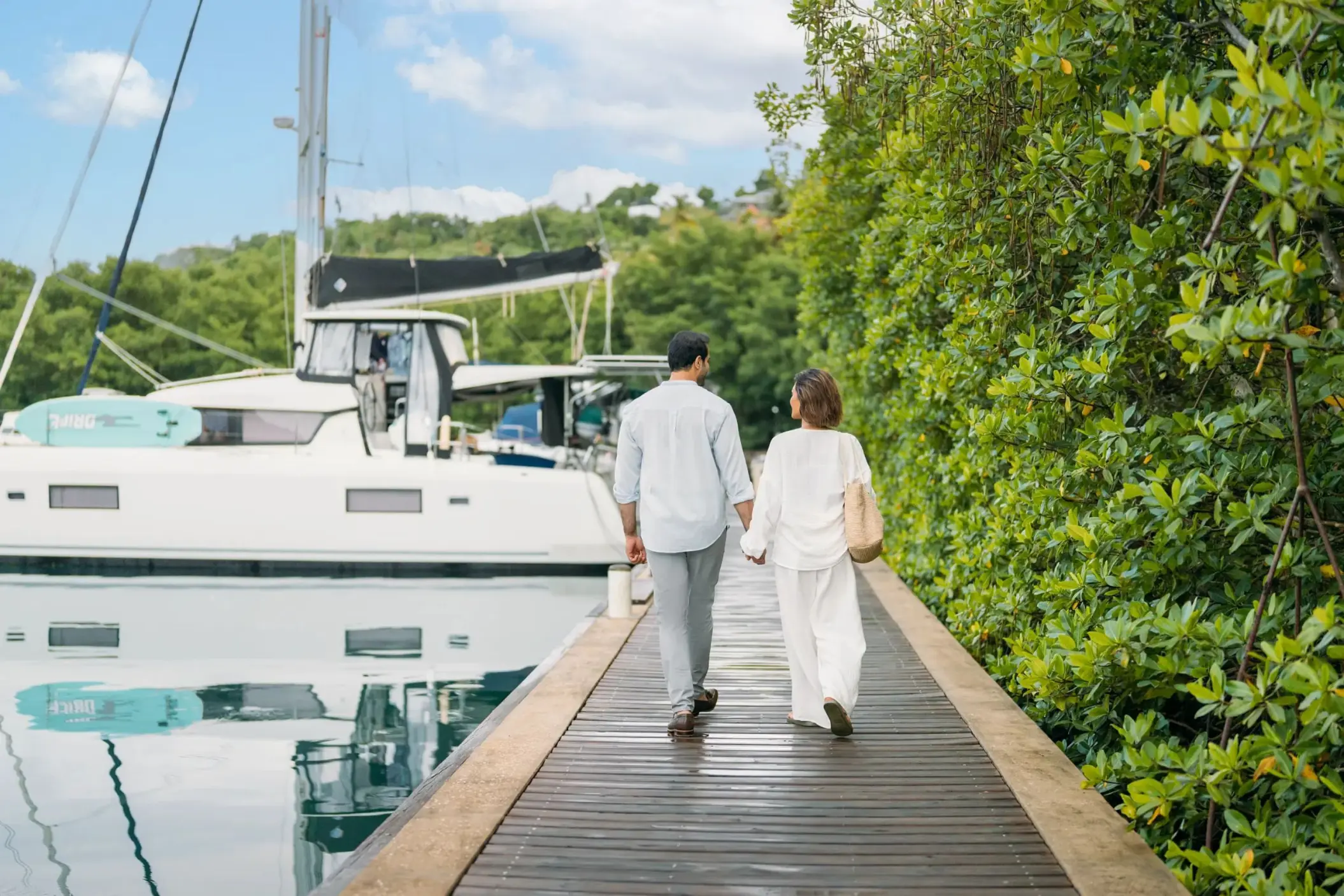 Couple walking down the wooden marina dock at Zoetry Marigot Bay, Castries