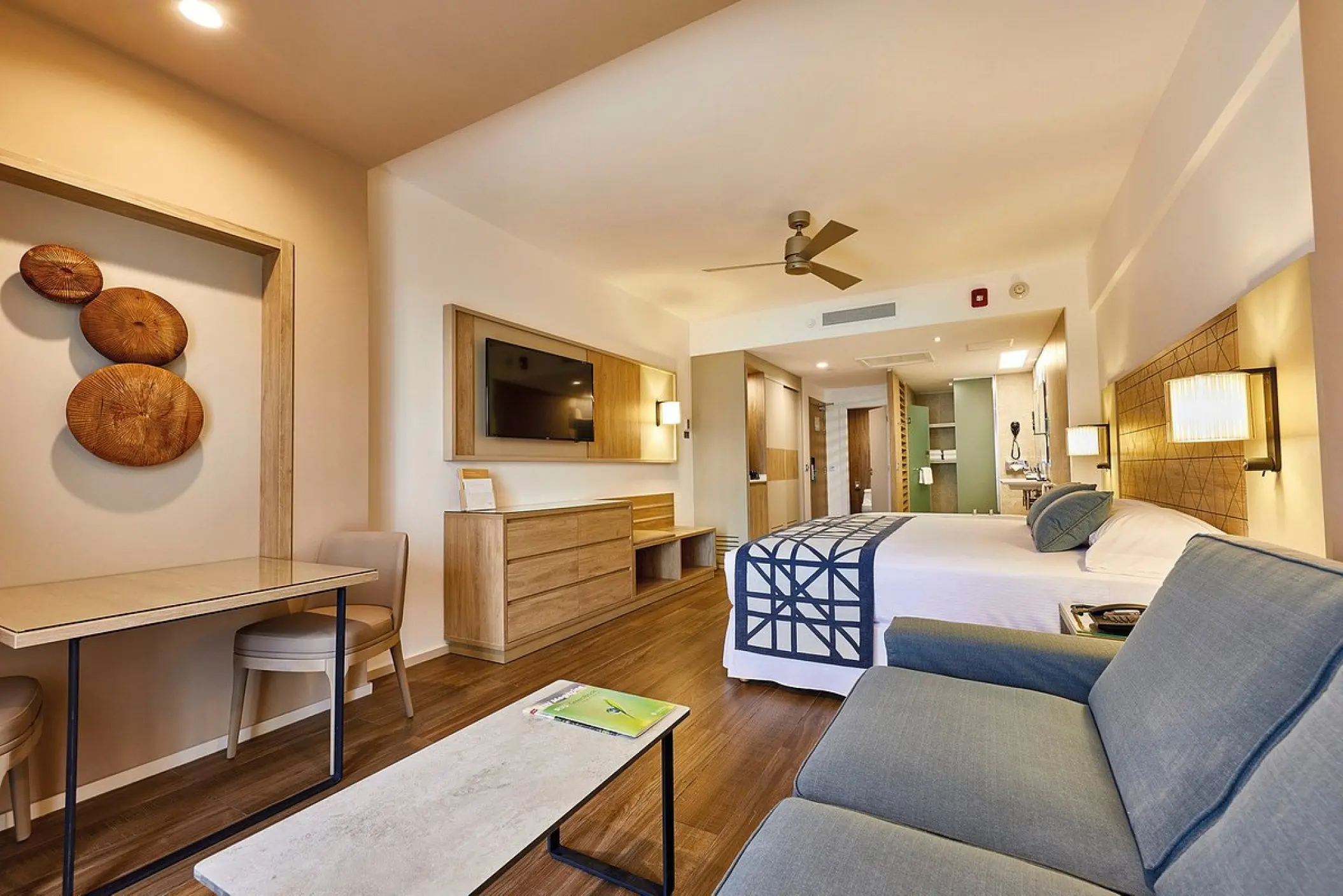 Junior suite with a blue sofa and wood accents at Riu Palace Baja California, Cabo San Lucas