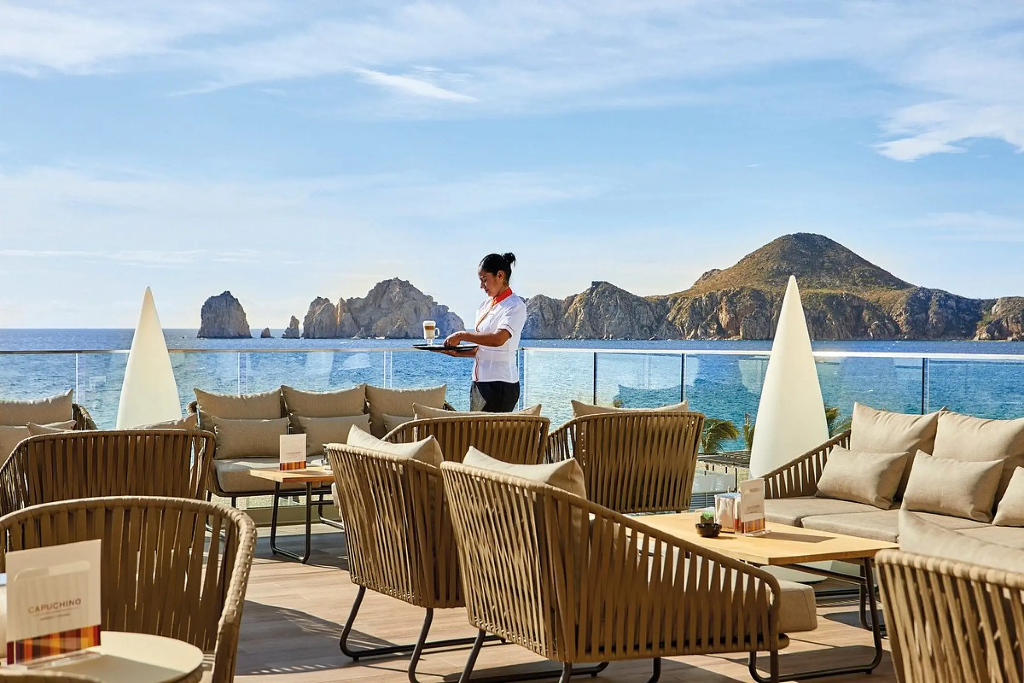 Outdoor terrace seating with ocean views and rock formations at Riu Palace Baja California, Cabo San Lucas