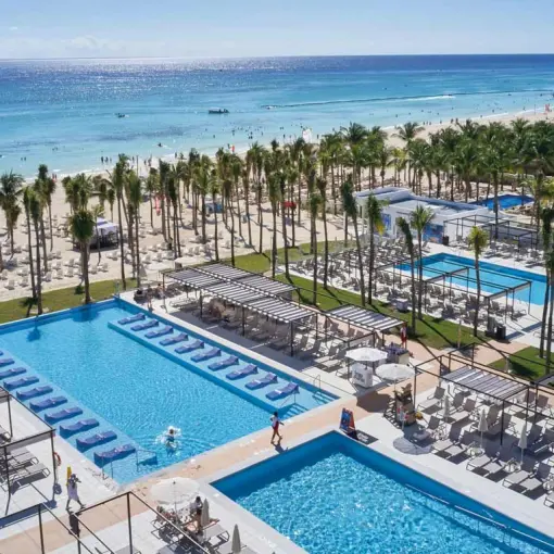 Aerial view of the pools, palm trees, and beachfront at Riu Palace Riviera Maya, Playa Del Carmen
