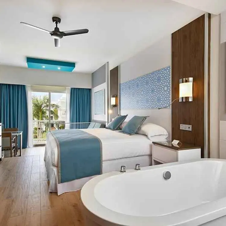 Modern guest room with a white bathtub and balcony at Riu Palace Riviera Maya, Playa Del Carmen
