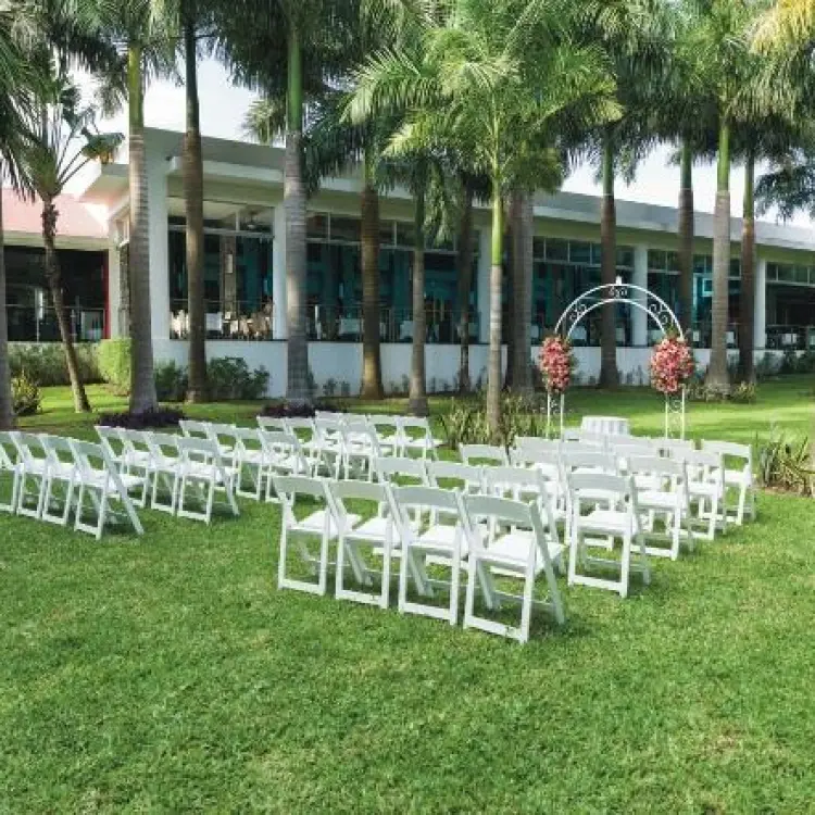 Garden wedding ceremony setup with white chairs and floral arch at Riu Yucatan, Playa Del Carmen