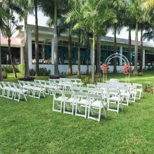 Garden wedding ceremony setup with white chairs and floral arch at Riu Yucatan, Playa Del Carmen