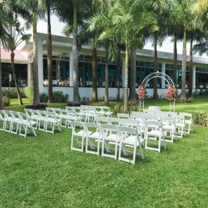 Garden wedding ceremony setup with white chairs and floral arch at Riu Yucatan, Playa Del Carmen