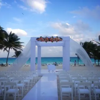 Beachfront wedding ceremony with a white huppah and lavender floral accents at Riu Palace Costa Mujeres, Cancun