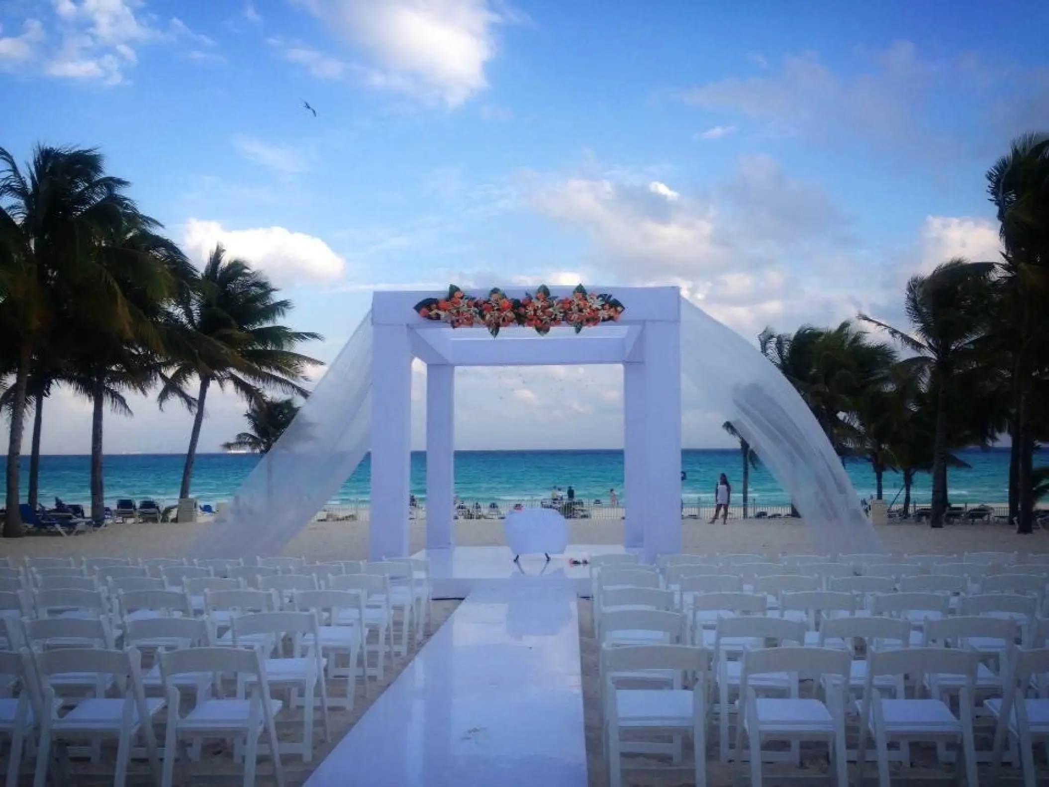 Beachfront wedding ceremony with a white huppah and lavender floral accents at Riu Palace Costa Mujeres, Cancun