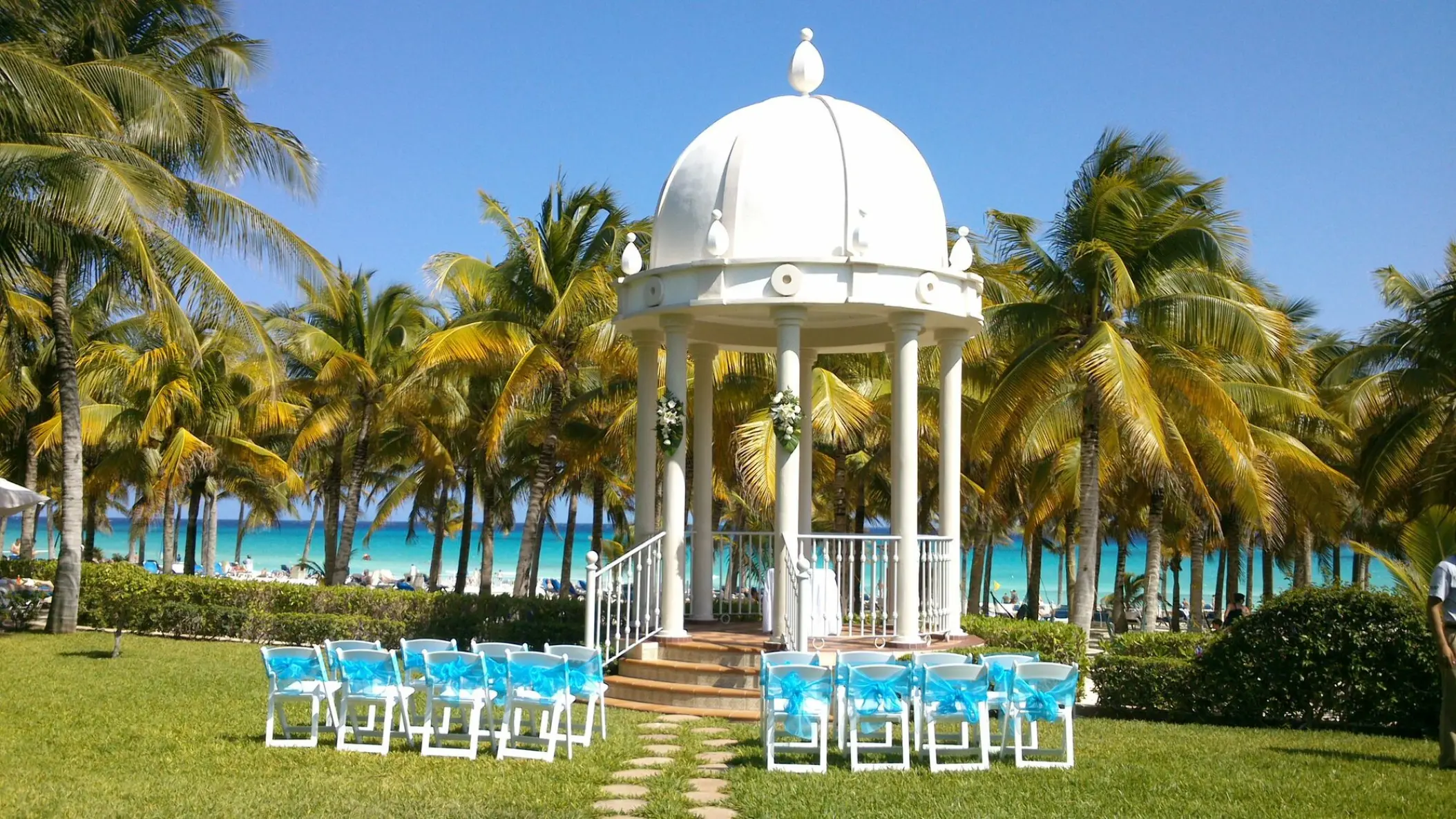 White gazebo wedding ceremony venue with blue chairs at Riu Palace Costa Mujeres, Cancun