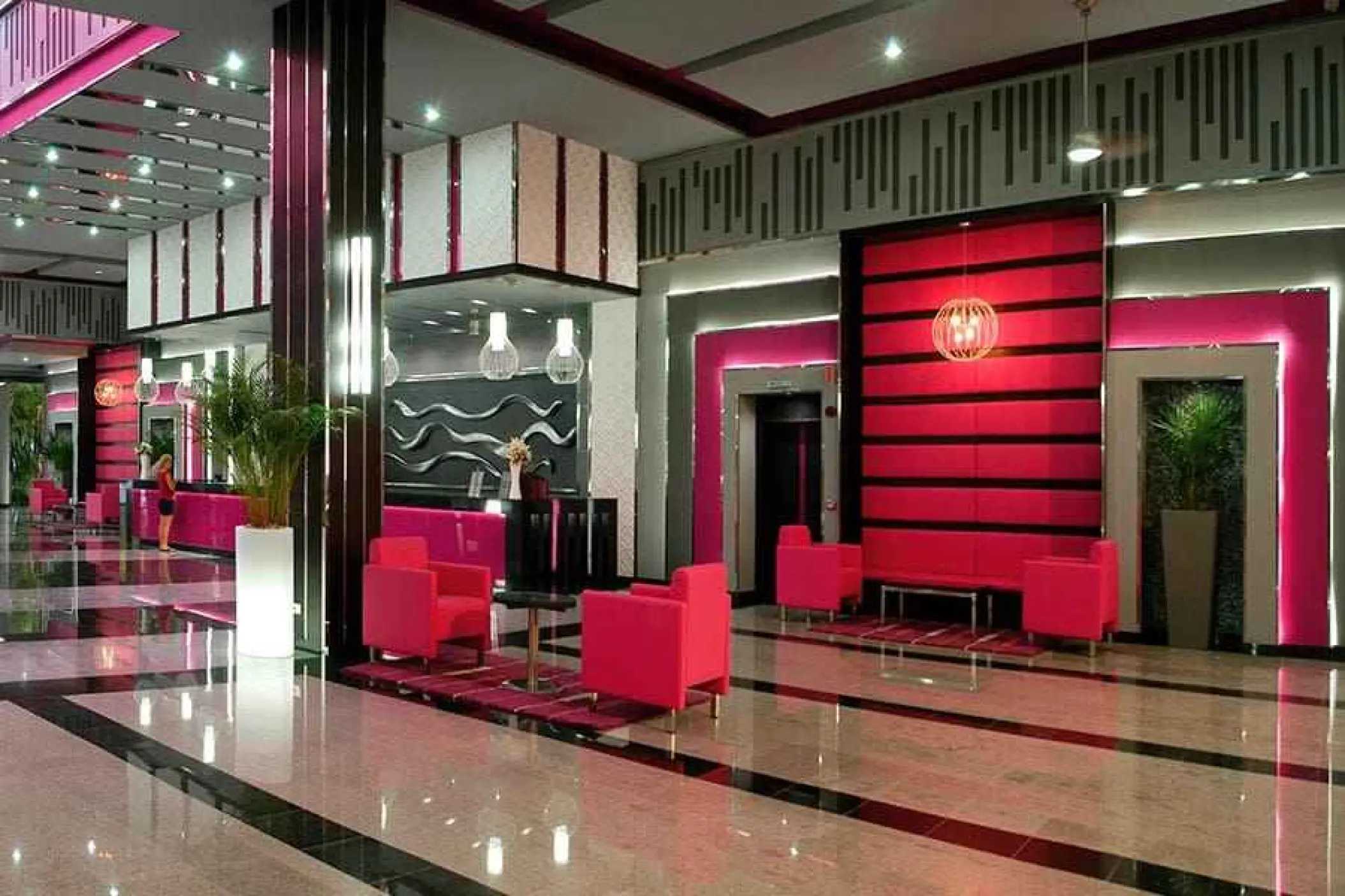 Modern lobby with pink chairs and neon accents at Riu Yucatan, Playa Del Carmen