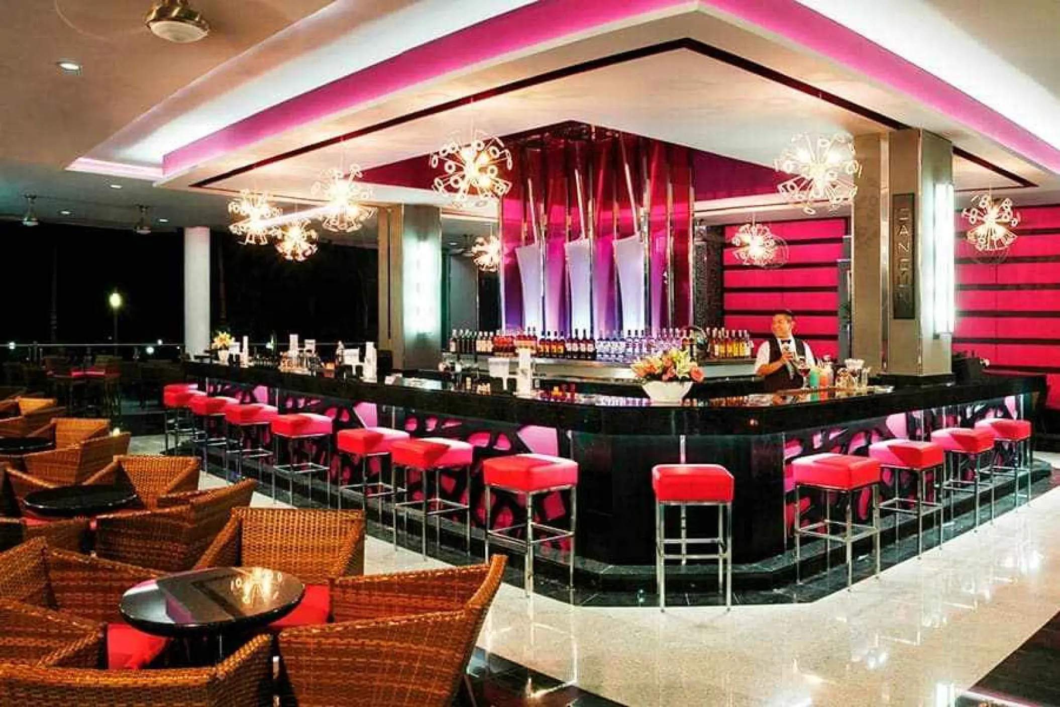 Modern lobby bar with pink lighting and red barstools at Riu Yucatan, Playa Del Carmen