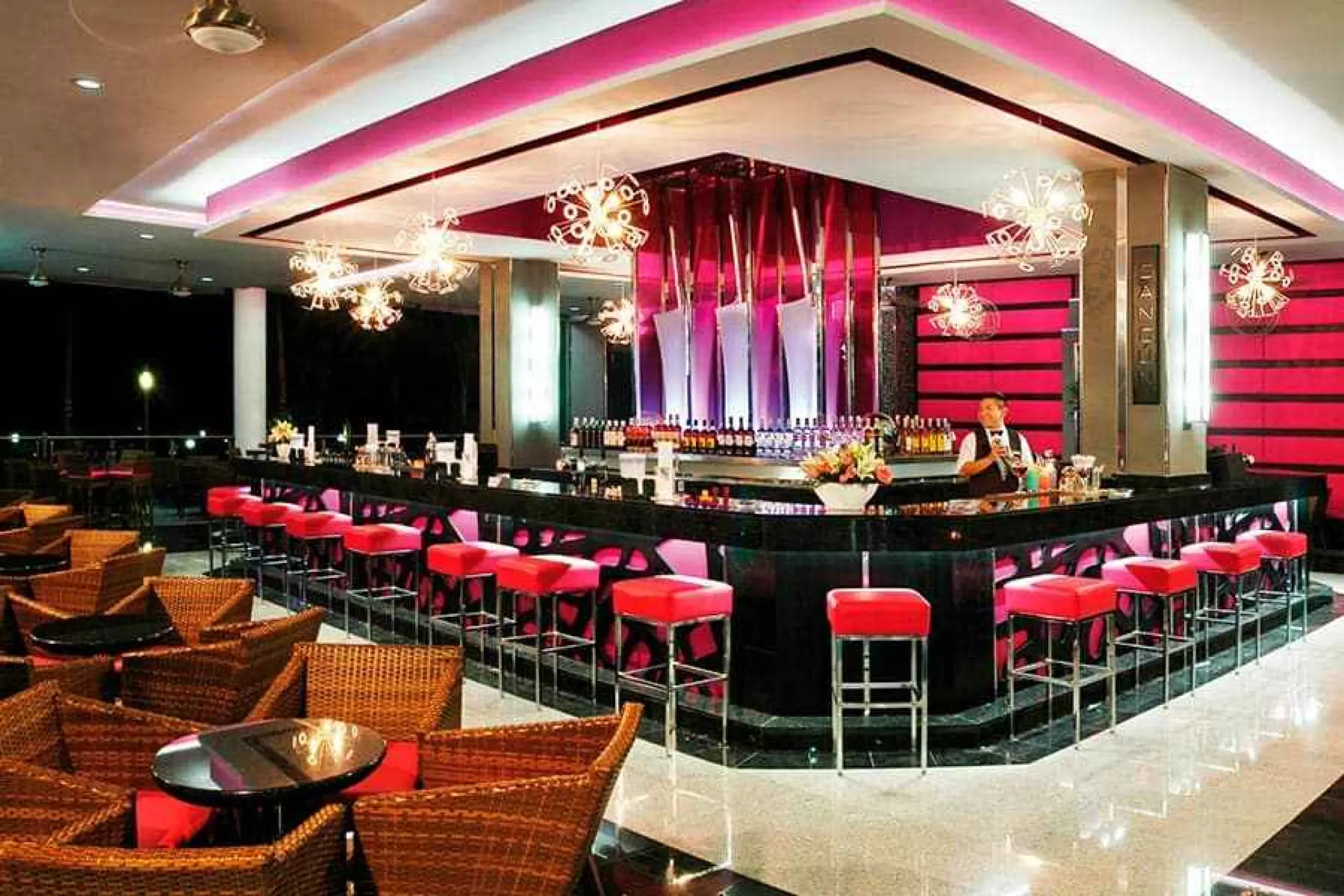 Modern lobby bar with pink lighting and red barstools at Riu Yucatan, Playa Del Carmen