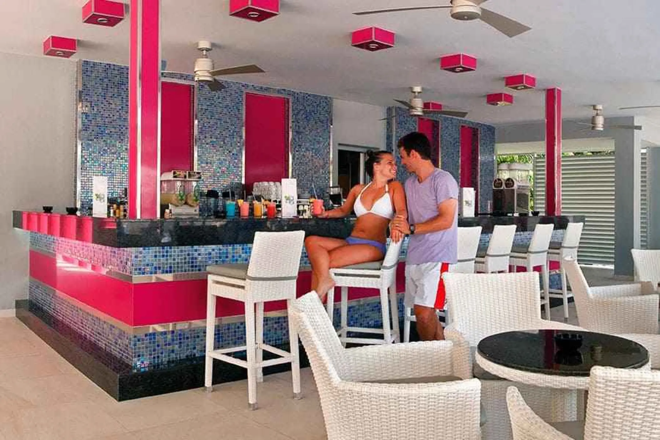Couple enjoying drinks at the colorful poolside bar at Riu Yucatan, Playa Del Carmen