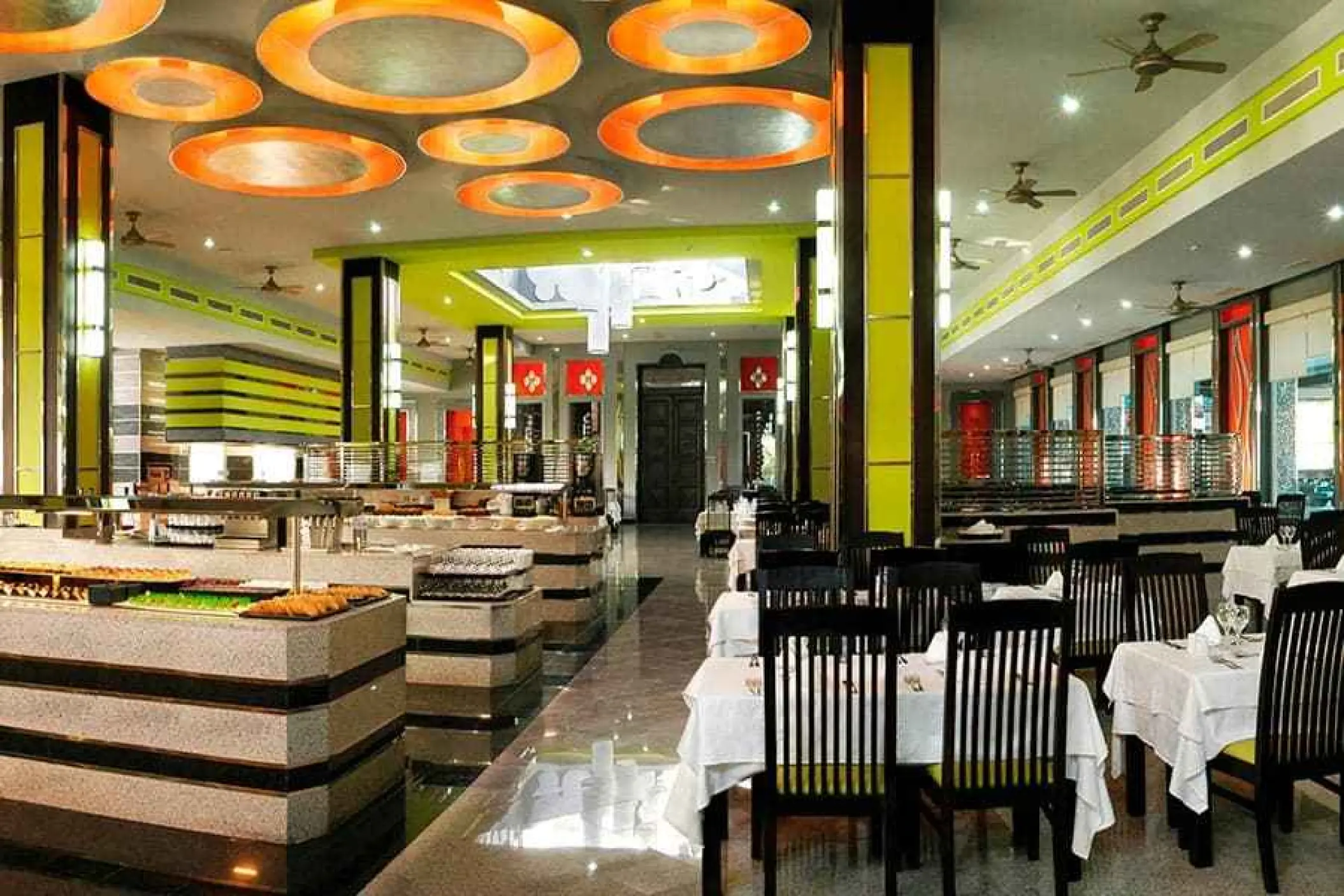 Modern buffet and dining area with orange circular ceiling lights at Riu Yucatan, Playa Del Carmen