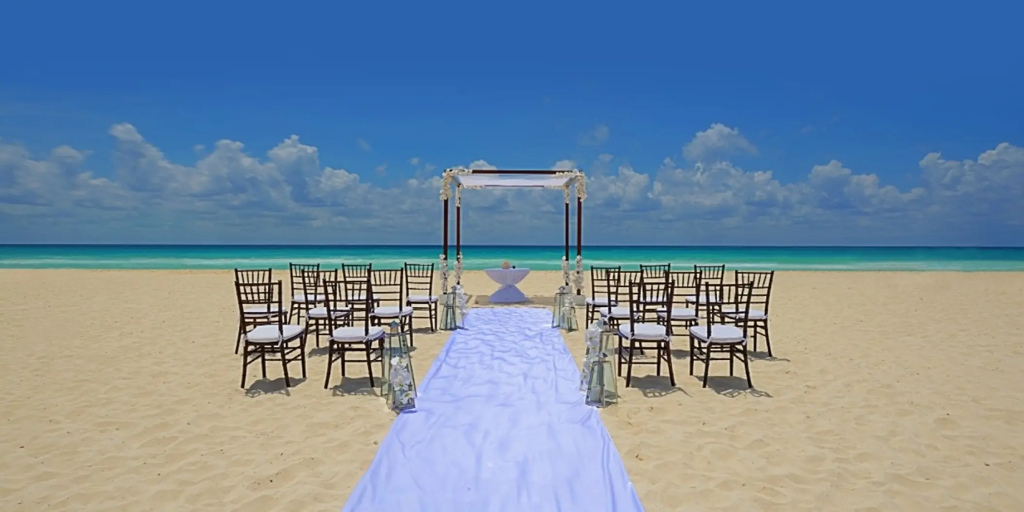 Beachfront wedding ceremony with a white huppah and aisle runner at Royal Hideaway Playacar, Playa Del Carmen