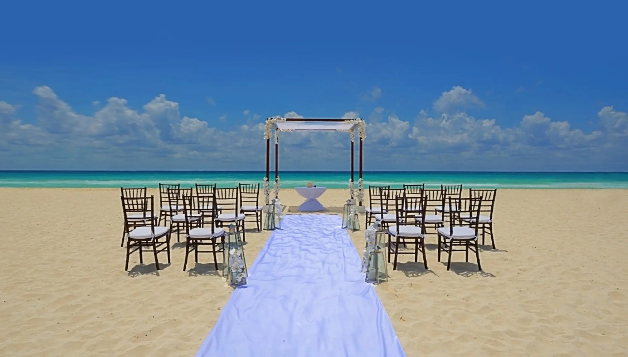 Beachfront wedding ceremony with a white huppah and aisle runner at Royal Hideaway Playacar, Playa Del Carmen