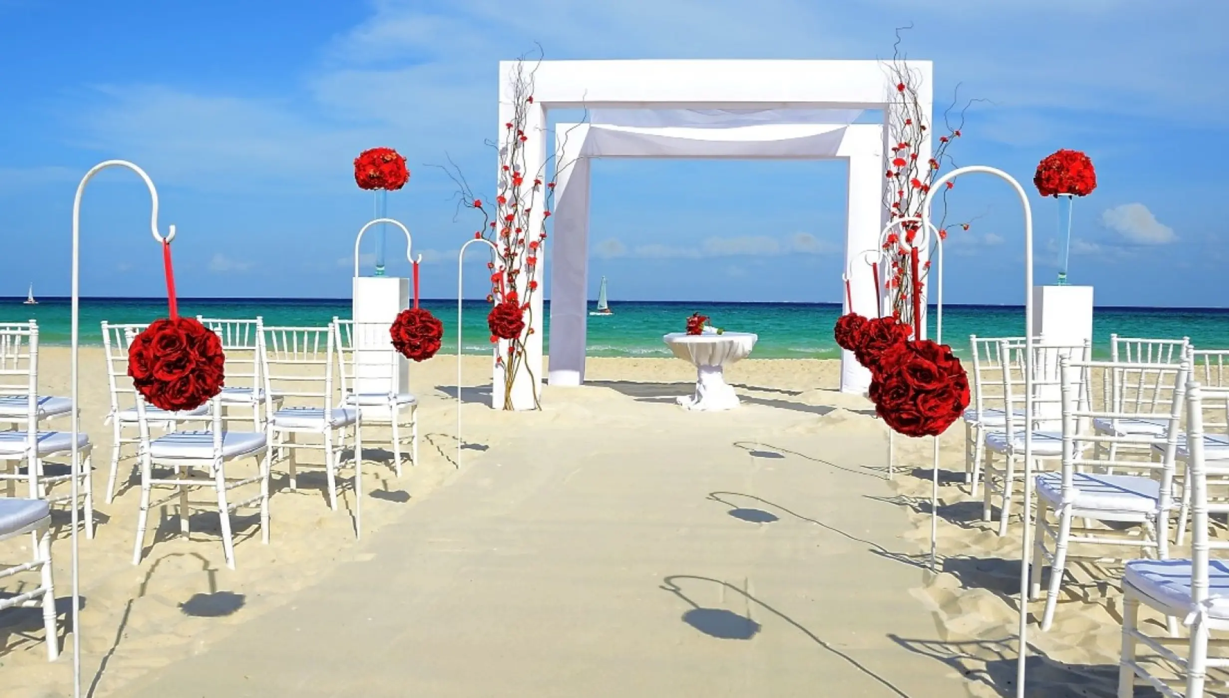 Beachfront wedding ceremony setup with red floral accents at Royal Hideaway Playacar, Playa Del Carmen