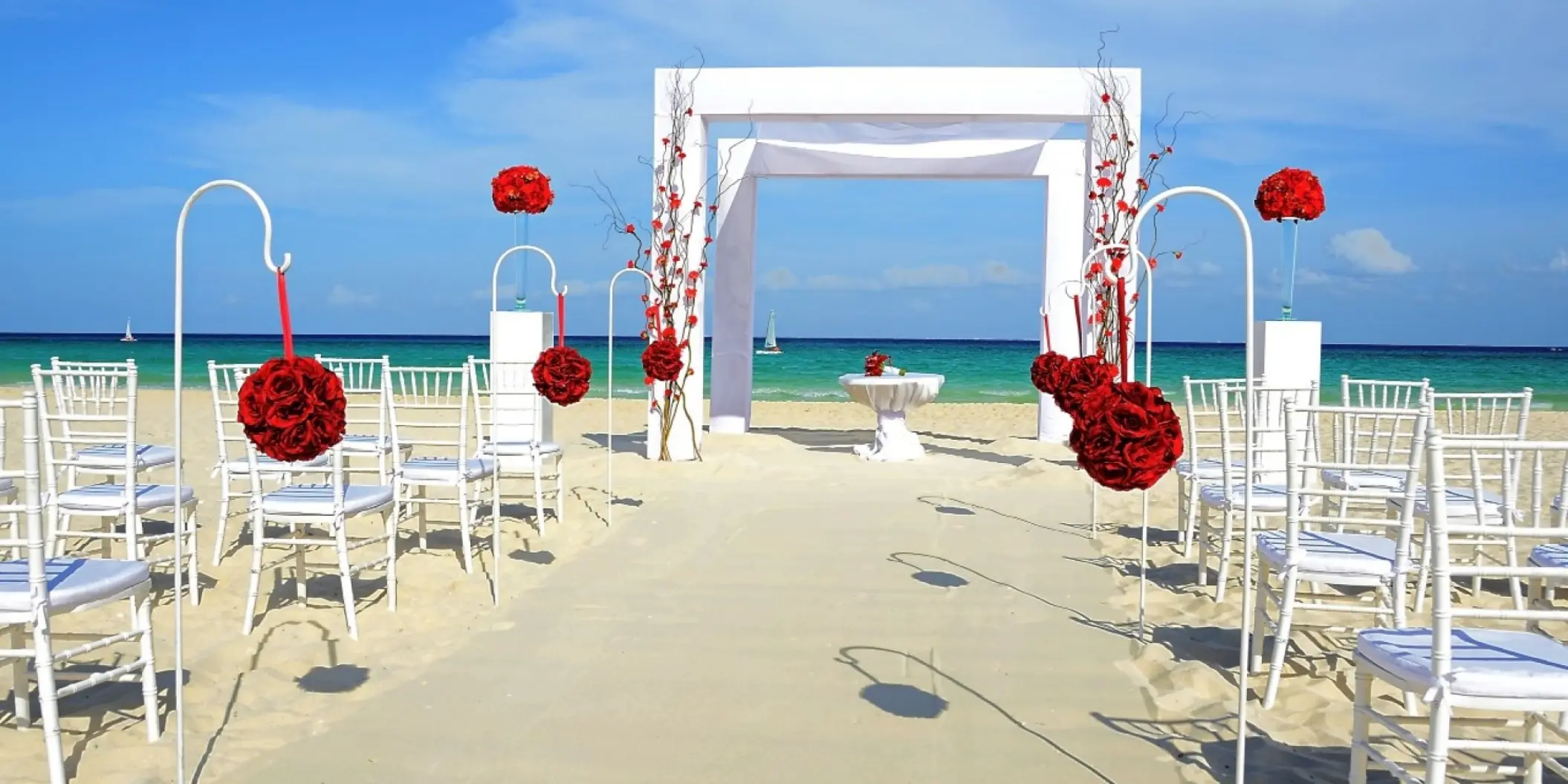 Beachfront wedding ceremony setup with red floral accents at Royal Hideaway Playacar, Playa Del Carmen