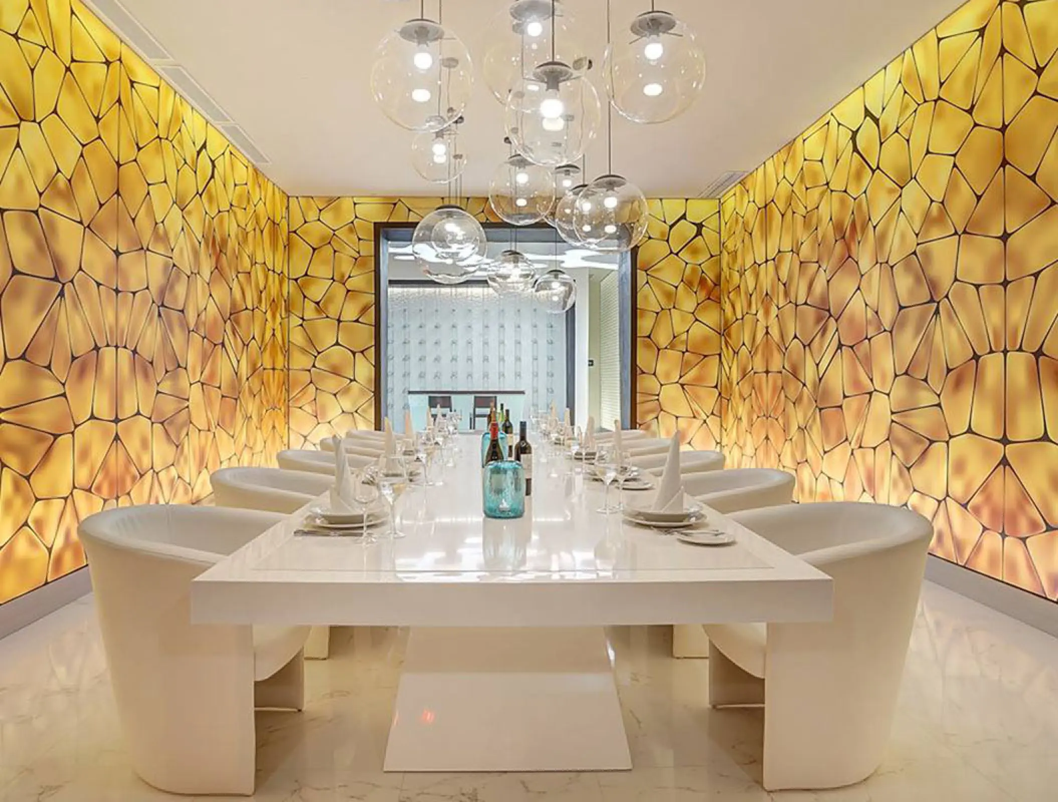 Modern dining room with glowing gold walls and spherical pendants at Royalton Blue Waters, Montego Bay