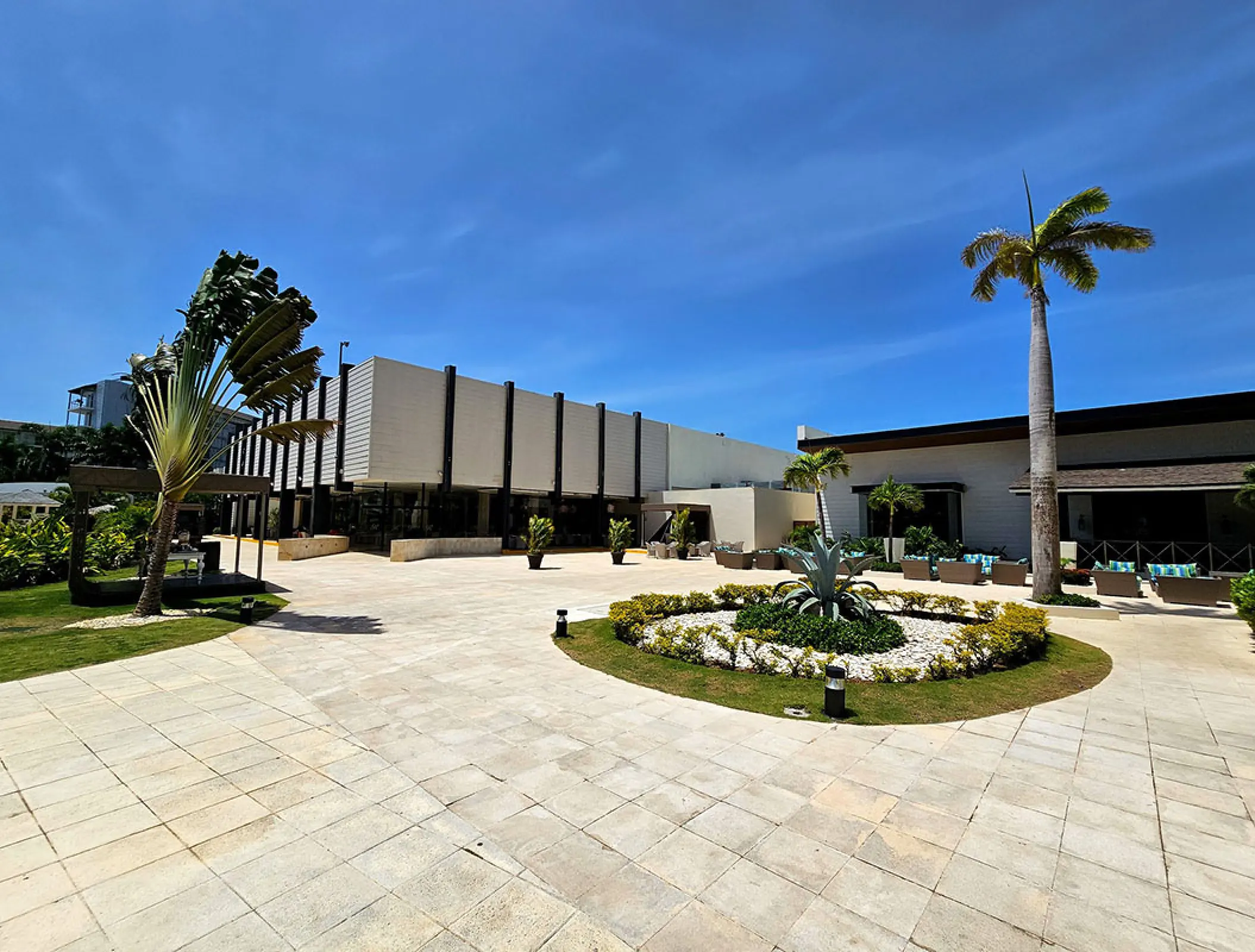 Central plaza with palm trees and modern buildings at Royalton Blue Waters, Montego Bay