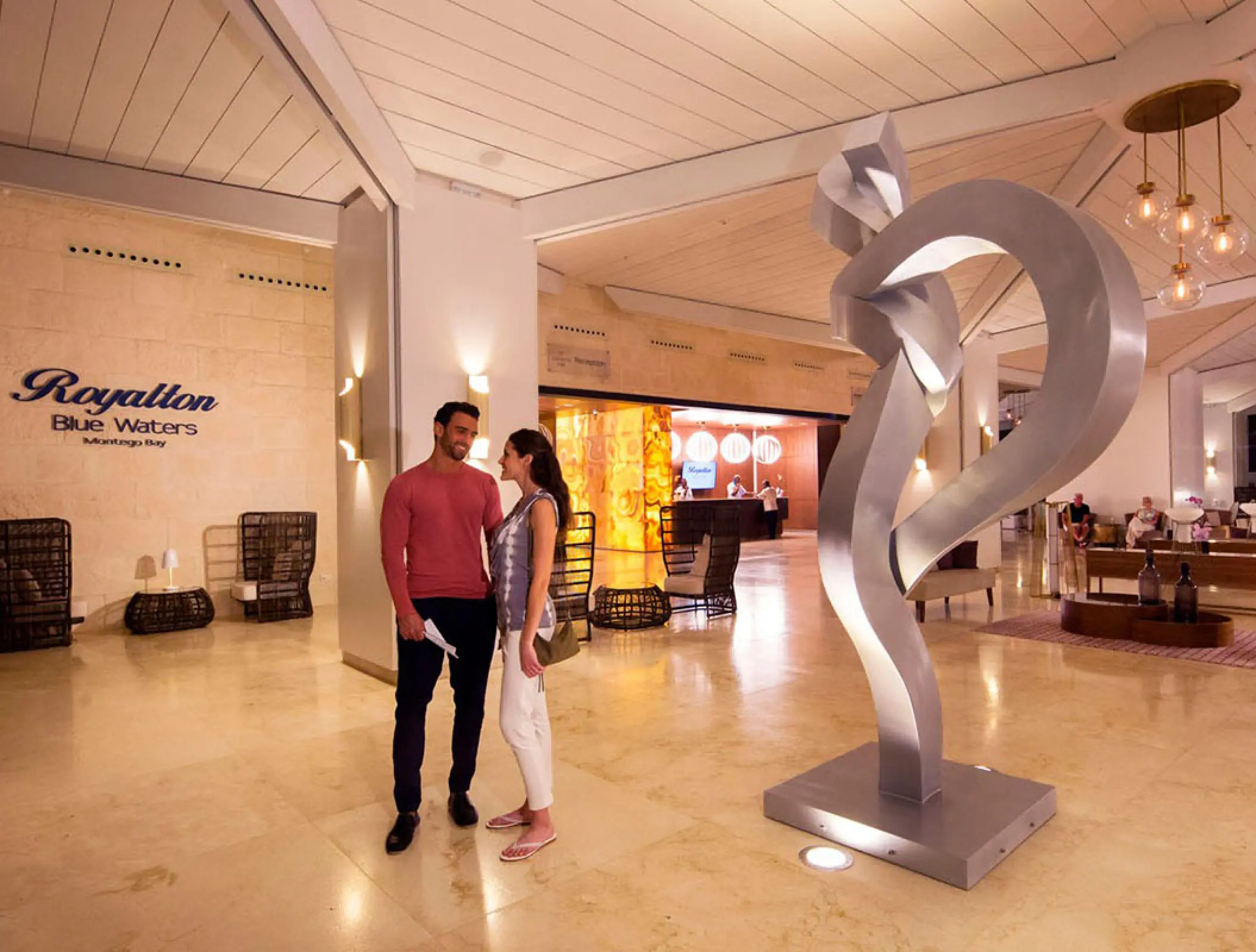 Modern lobby with abstract sculpture and a couple at Royalton Blue Waters, Montego Bay