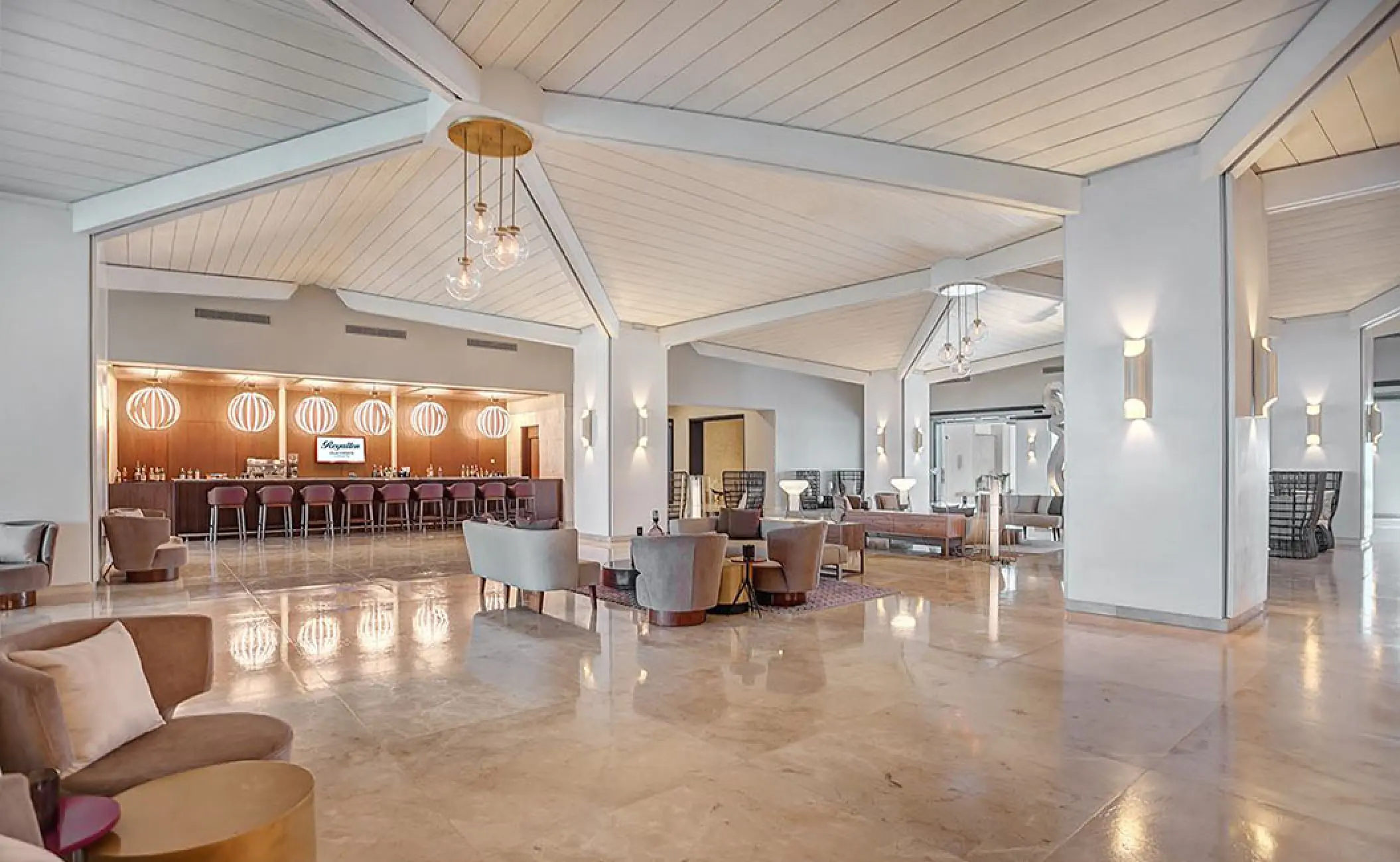 Modern open-concept lobby with polished floors and a bar at Royalton Blue Waters, Montego Bay