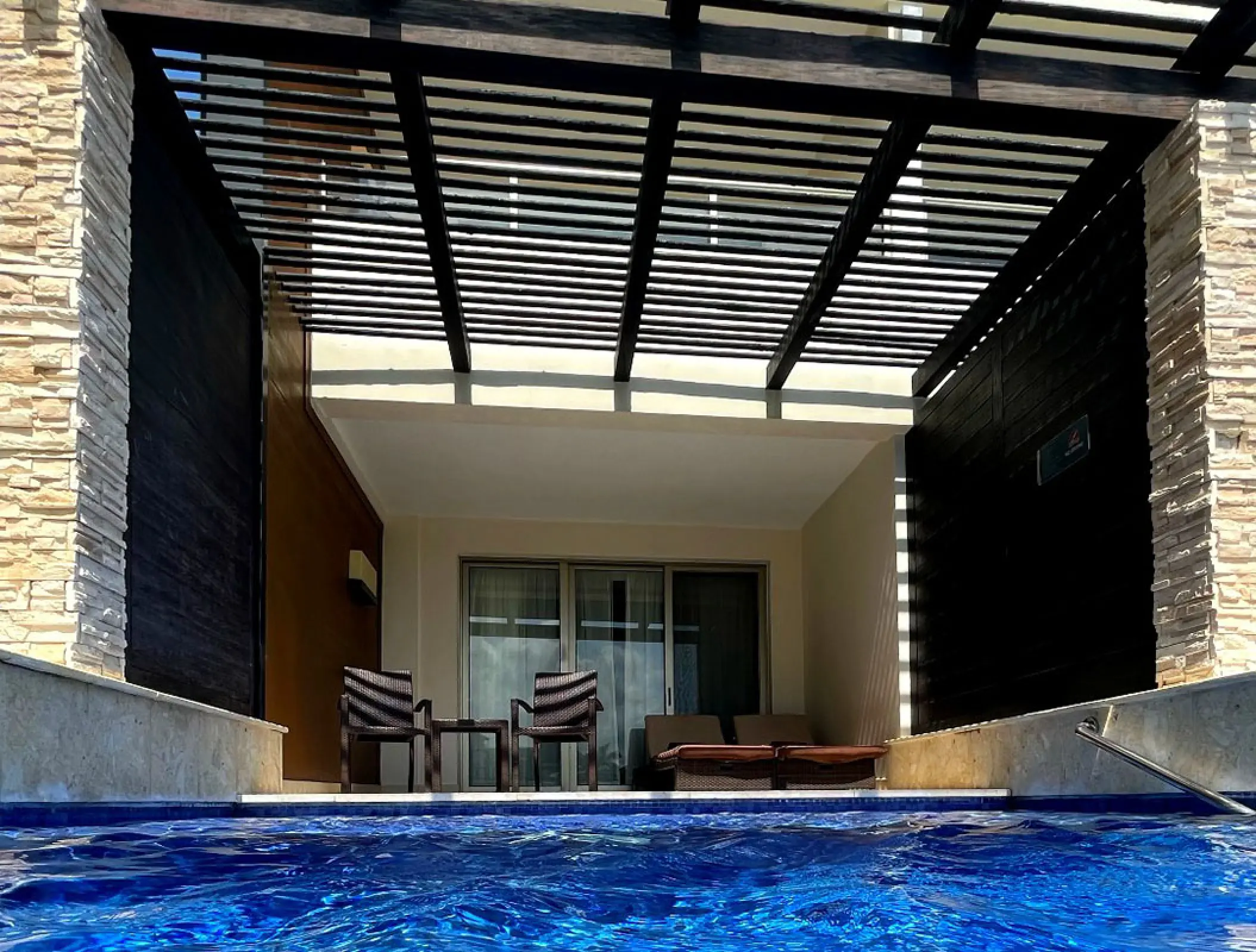 Swim-up pool and private terrace under a dark wood pergola at Royalton Blue Waters, Montego Bay