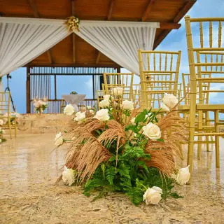 Wedding ceremony setup at Royalton Blue Waters with white flowers and gold chairs, Montego Bay