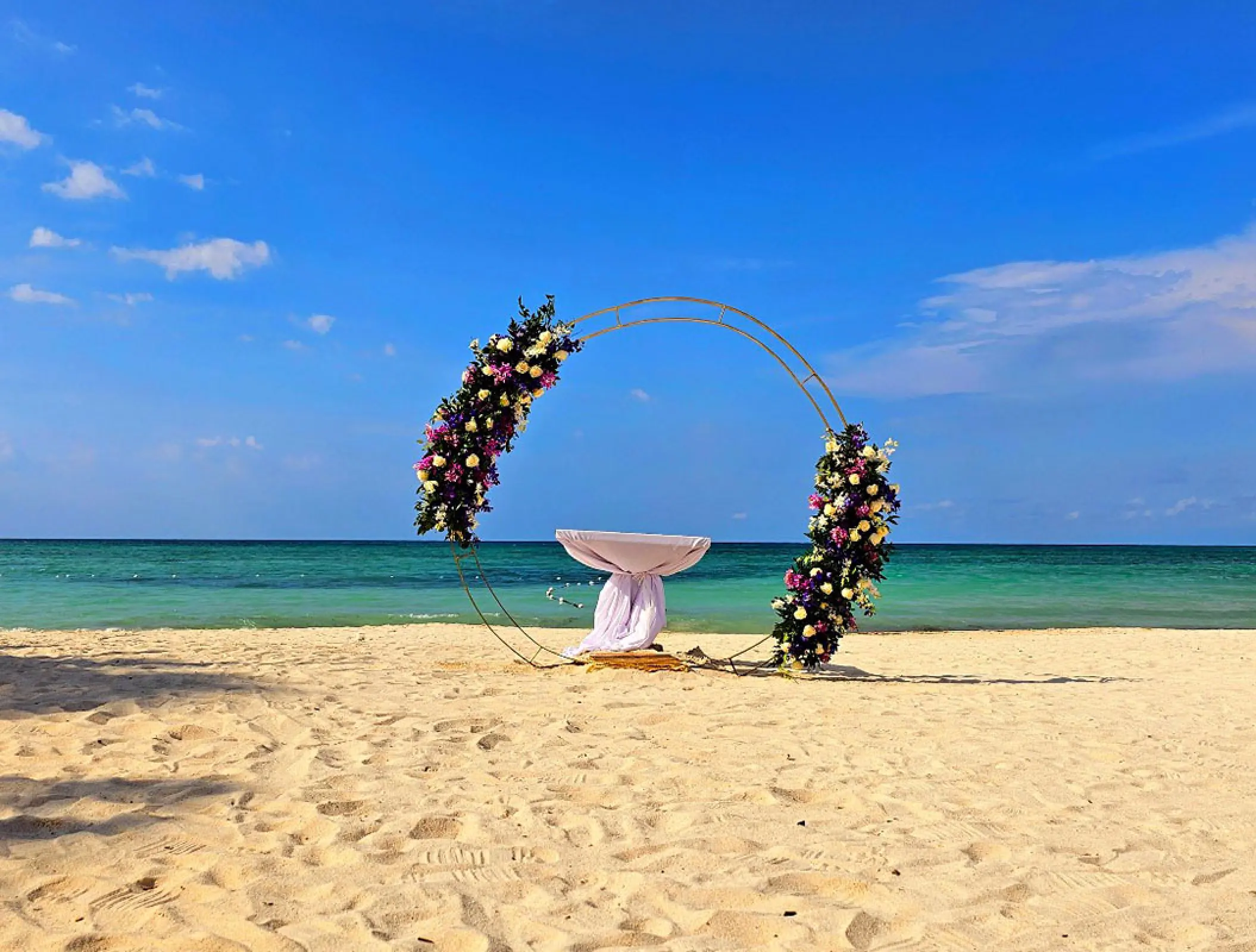 Circular floral wedding ceremony arch on the beach at Royalton Blue Waters, Montego Bay