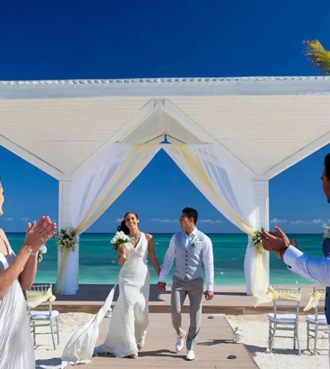 Newlyweds walking down the aisle at a beach ceremony at Royalton Blue Waters, Montego Bay